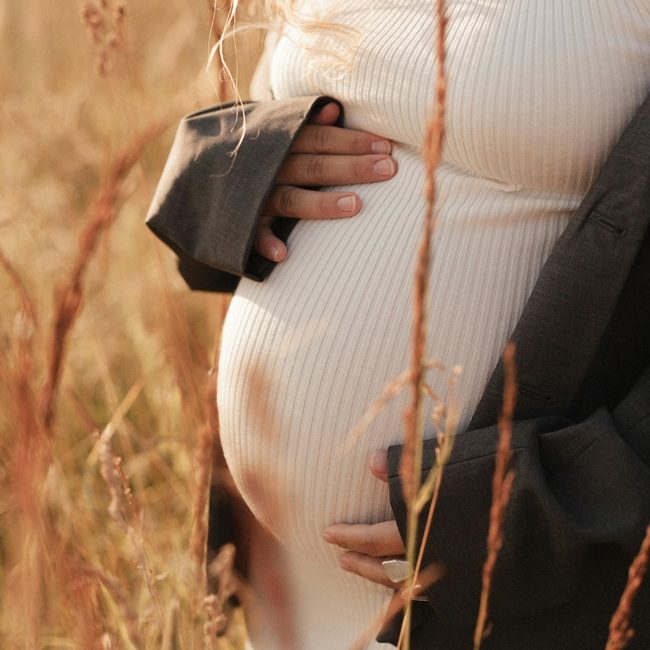 schwangere Frau im Sonnenuntergang auf Feld interessiert sich für Hypnobirthing