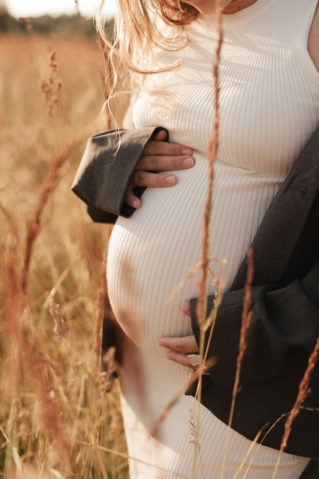 schwangere Frau im Sonnenuntergang auf Feld interessiert sich für Hypnobirthing