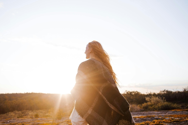 Frau im Sonnenaufgang mit Decke um die Schultern vertraut ihrer Intuition